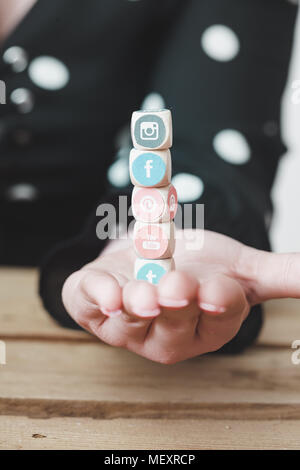 Berlino, 5 aprile 2018: giovane persona d'affari tenendo a cubetti con loghi di più social network di siti web, immagine simbolica per la gestione di pub online Foto Stock