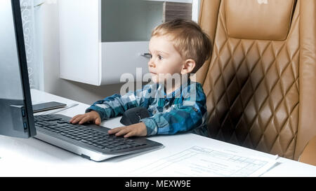 Ritratto di adorabili toddler boy utilizzando computer in ufficio Foto Stock