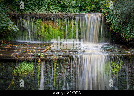Una piccola cascata su man-made scarpata a gradino lungo il ramo di primavera Canal a Skipton, North Yorkshire, Regno Unito. Foto Stock