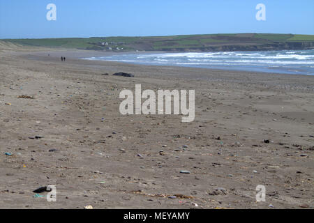 Giovane camminando su un vuoto di spiaggia di sabbia in una luminosa giornata d'estate con la rottura delle onde in rotolamento su una brezza di mare. Spiaggia Owenahincha Irlanda. Foto Stock