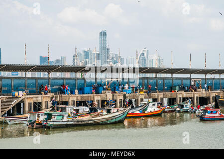 Panama City, Panama - marzo 2018: i pescatori e barche sul mercato del pesce / Harbour con lo skyline della citta', Panama City. Foto Stock