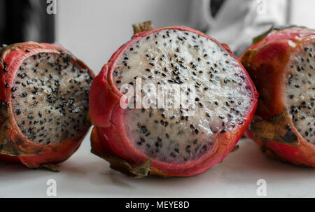 Tagliate a fette il drago rosso pitaya frutto su una finestra bianca dello sfondo. Primo piano. Foto Stock