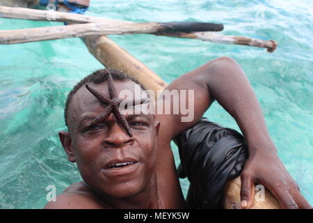 L'uomo africano con starfish sulla faccia, Zanzibar, Tanzania Foto Stock