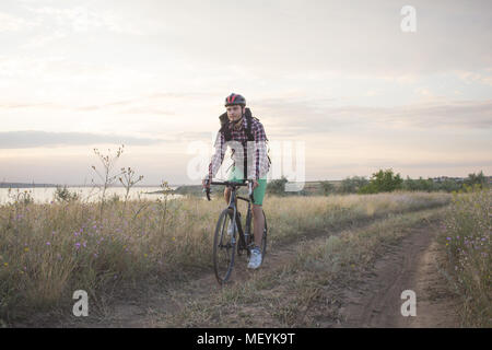 Giovane uomo traveler ride all'aperto sulla bicicletta da ciclocross rider in abbigliamento casual con zaini Foto Stock