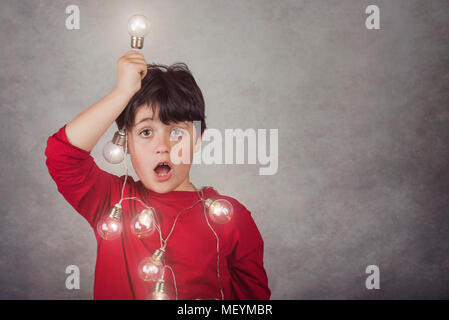 Ragazzo sorpreso con lampadine su sfondo grigio Foto Stock