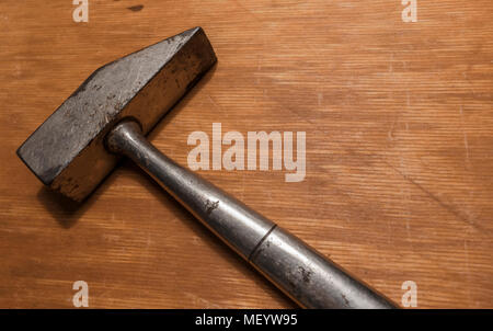 Vecchio martello in acciaio close-up su un graffiato scrivania in legno. Foto del martello in acciaio con spazio di copia Foto Stock