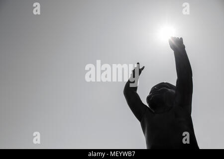 Luminose Sogni di bimbo realizzato in scultura. Statua di bronzo di un ragazzino che punti al cielo e sostiene il sole nella sua mano. Foto Stock