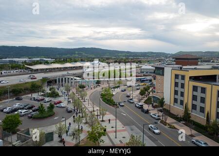 Vista aerea del Dublin Pleasanton Bay Area Rapid Transit (BART) Commuter Rail Station nel centro cittadino di Dublino, California, con montagne e edifici appartamento visibile su un giorno nuvoloso, con autostrada 580 visibile in background, Aprile 9, 2018. () Foto Stock