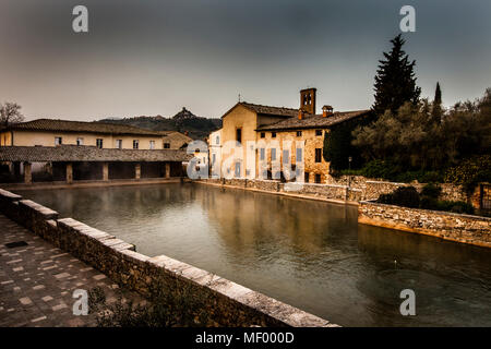 Nel centro di bagno Vignoni domina l'antica piscina termale. Oggi la piscina è un monumento protetto e qui è vietato fare il bagno. Ma il fascino del vecchio luogo di balneazione è perfettamente conservato. Numerosi caffè e ristoranti fiancheggiano il sito storico, che spesso è stato lo sfondo per i film. Foto Stock