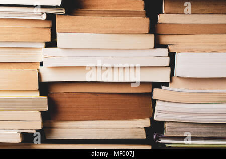 Pile di vecchi e nuovi libri di testo, impilati e telaio di riempimento. Retrò filtrato in toni caldi. Foto Stock