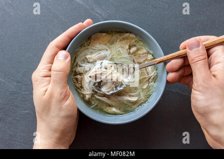 Zuppa asiatica di anatra con mani di uomo nero su sfondo di pietra Foto Stock