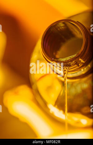 Flusso liquido di moto motor olio fluisce dal collo della bottiglia di close-up. Foto Stock