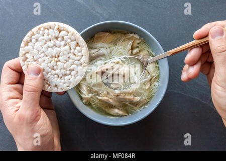 Zuppa asiatica di anatra con mani di uomo nero su sfondo di pietra Foto Stock