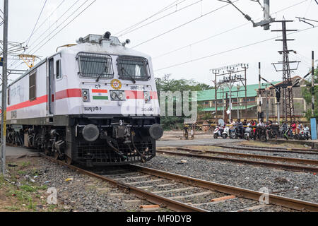 Pondicherry, India - 17 Marzo 2018: una locomotiva alla parte anteriore di un treno passeggeri passando al di sopra di un passaggio a livello fuori dalla stazione principale Foto Stock