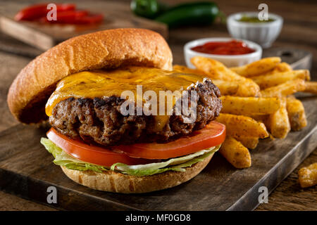 Una deliziosa casa burger reale con il formaggio cheddar e pepe nero condito patatine fritte. Foto Stock