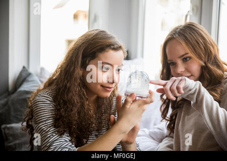 Due ragazze adolescenti con snow globe a casa Foto Stock