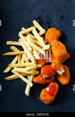 Pepite di pollo con salsa al peperoncino dolce e patatine fritte sul terreno scuro Foto Stock