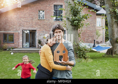 Ritratto di Coppia sorridente con la figlia nel giardino della loro casa azienda modello di casa Foto Stock