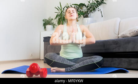 Giovane donna seduta in lotus yoga virtù e profondamente la respirazione Foto Stock
