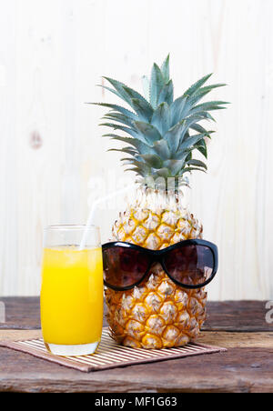 Ananas con gli occhiali in estate concetto. E un bicchiere di succo di ananas accanto a. Foto Stock