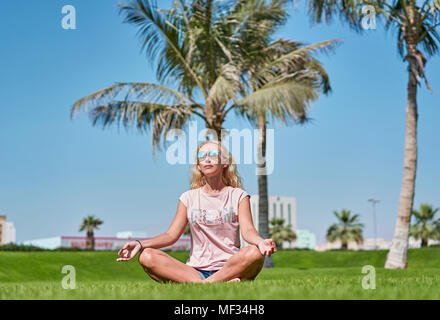 Ragazza medita seduto sull'erba Foto Stock