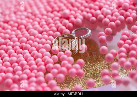 Oro giallo e oro bianco anello di nozze con diamante rosa sfere e bolle in background. Vassoio originali per la cerimonia del matrimonio. Foto Stock