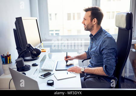 Sorridente graphic designer che lavora sul computer alla scrivania in ufficio Foto Stock