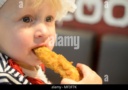 Ritratto di un anno di età e gli otto mesi bambino e bambina a mangiare una ala di pollo Foto Stock