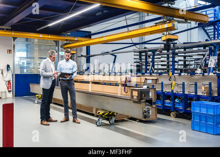 Uomini d'affari durante la riunione con gli appunti in sala di produzione Foto Stock
