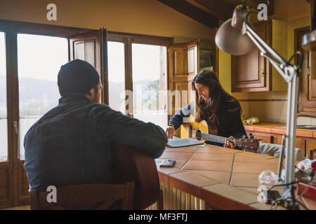 Coppia giovane a suonare la chitarra a tavola in casa Foto Stock