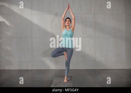 Giovane donna facendo esercizio di yoga in studio Foto Stock