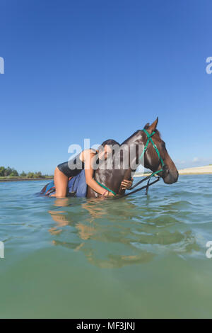 Indonesia, Bali, donna sdraiata sul cavallo, in acqua Foto Stock