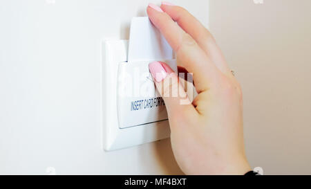 Primo piano immagine della giovane donna in camera di albergo inserendo la key card nel supporto Foto Stock