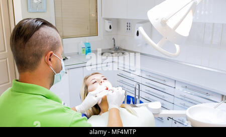 Primo piano immagine di dentista di guanti protettivi di ispezionare i denti della donna Foto Stock