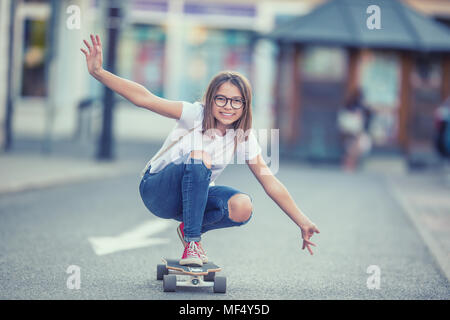 Tagliare il giovane skater girl cavalcare il suo longboard nella città. Foto Stock