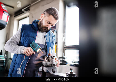 Uomo meccanico la riparazione di un auto in un garage. Foto Stock