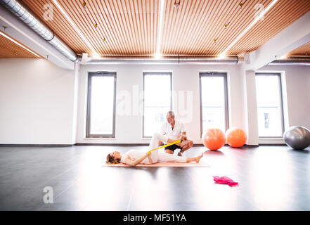 Senior fisioterapista maschio lavora con un paziente femmina. Foto Stock