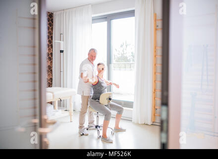 Senior fisioterapista maschio lavora con un paziente femmina. Foto Stock