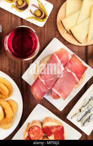 La cucina di Spagna. Una foto aerea di diversi tapas spagnoli, ripresa dall'alto su un rustico scuro texture. Jamon, formaggio, vino, e più, primo piano Foto Stock