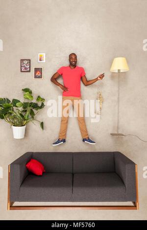 Uomo a casa nel suo soggiorno utilizza lo smartphone, ascoltando musica Foto Stock