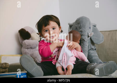 Ritratto di sorridente bambina gioca con la bambola a casa Foto Stock