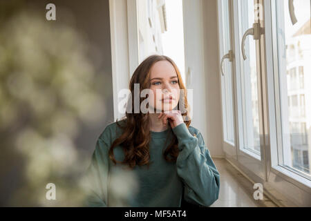 Ragazza adolescente guardando fuori della finestra, fantasticando Foto Stock