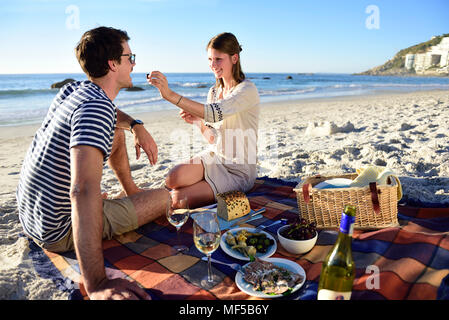 Felice coppia avente un picnic sulla spiaggia Foto Stock