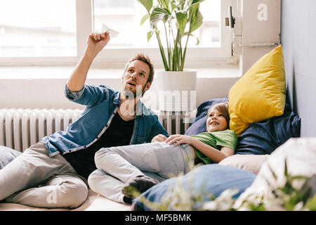 Padre e figlio giocare con aeroplano di carta a casa Foto Stock