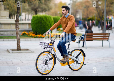 Spagna, Andalusia, Granada. Bel giovane sulla condivisione in bicicletta in città. Il concetto di stile di vita. Foto Stock