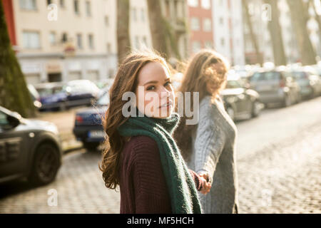 Ritratto di ragazza adolescente camminando mano nella mano con il suo migliore amico sulla strada Foto Stock