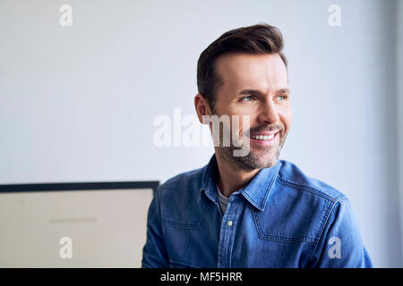 Ritratto di uomo sorridente in ufficio guardando lateralmente Foto Stock