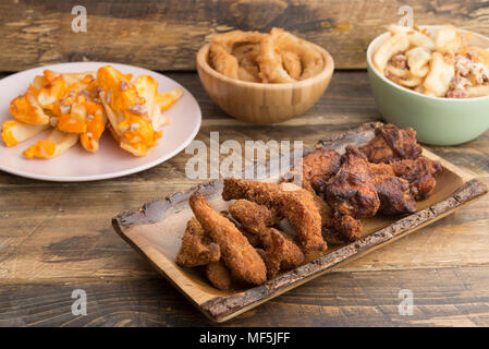 Tipica cucina americana, patate con formaggio e pancetta, anelli di cipolla fritti e ali di pollo Foto Stock