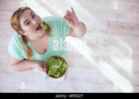 Paffuto giovane donna insalata mangiare Foto Stock