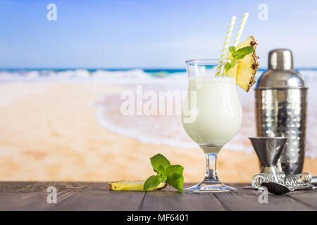 Il freddo La pina colada cocktail in un bicchiere sulla spiaggia con seascape sfondo Foto Stock